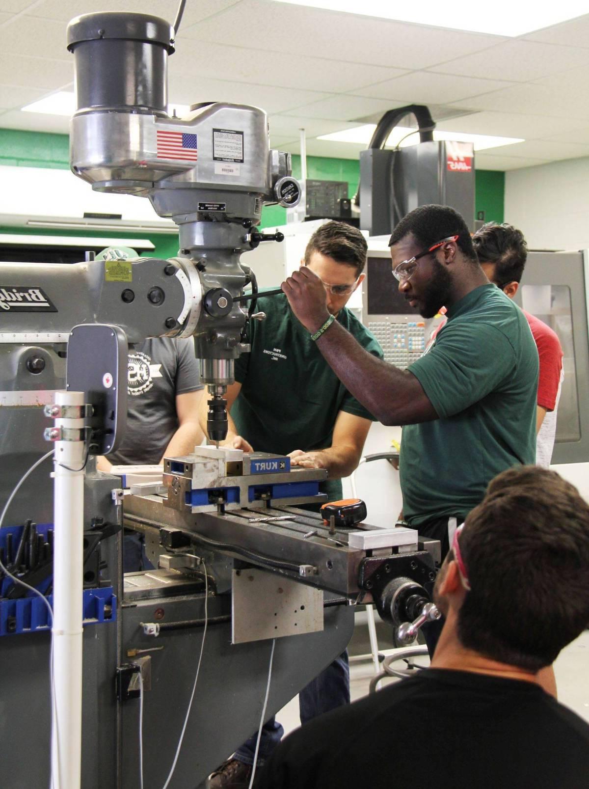 Mechanical engineer students working with engineering machinery.